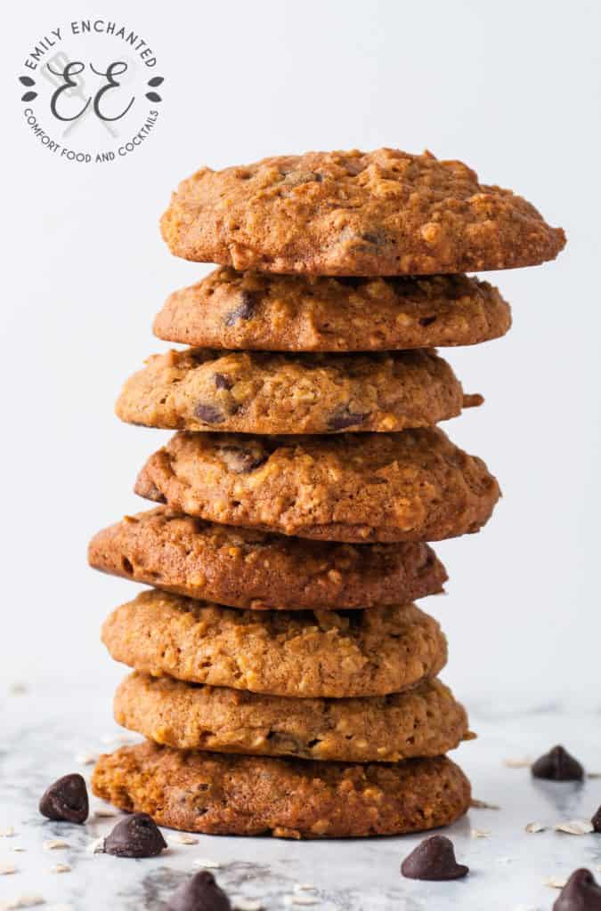 Stack of Oatmeal Pumpkin Chocolate Chip Cookies surrounded by loose chocolate chips on a marble counter top.