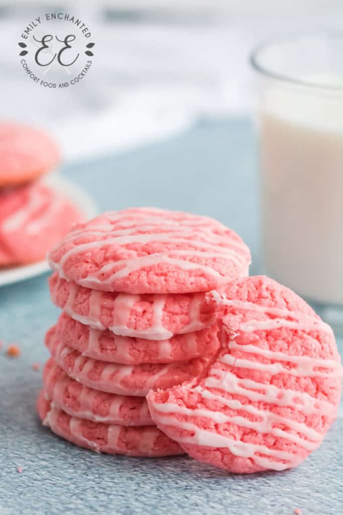 Strawberry Cake Mix Cookies with Icing #valentinesday #cookies #strawberry Strawberry Cake Mix Cookies stacked in a column with one cookie in front with a bite taken out of it