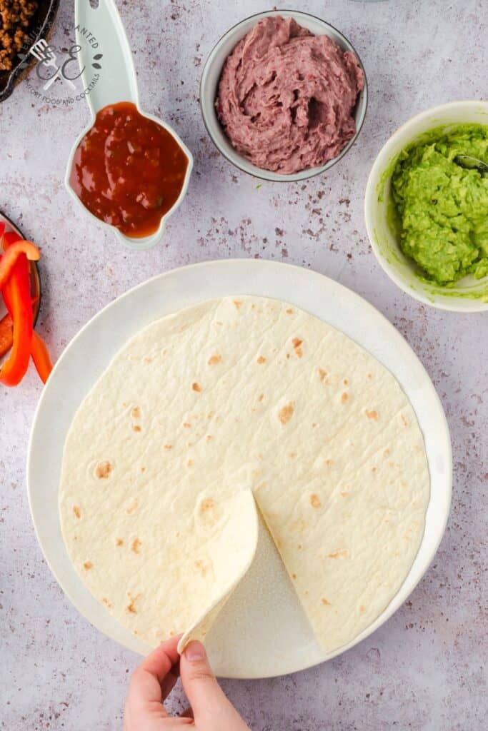 A Tortilla on a plate with one cut to the center.