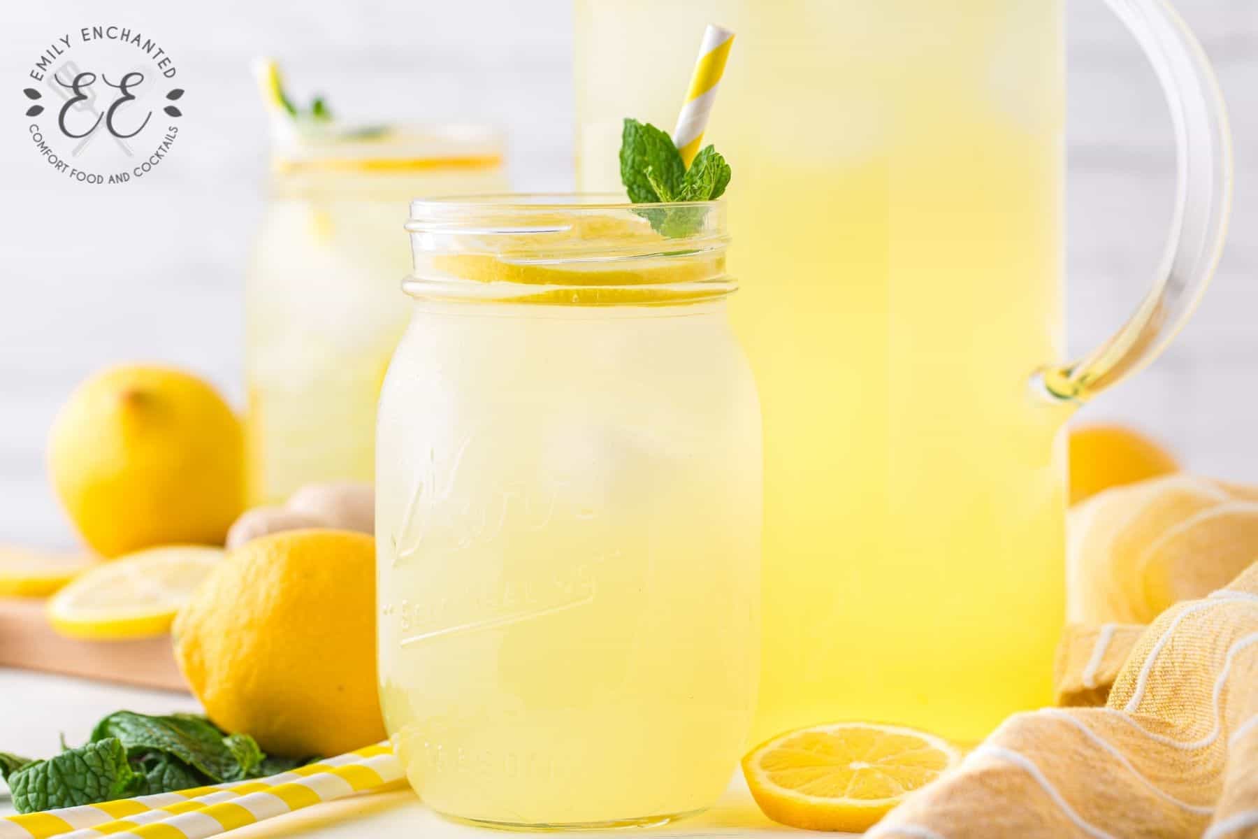 Ginger Mint Lemonade in a mason jar with pitcher and lemons in background