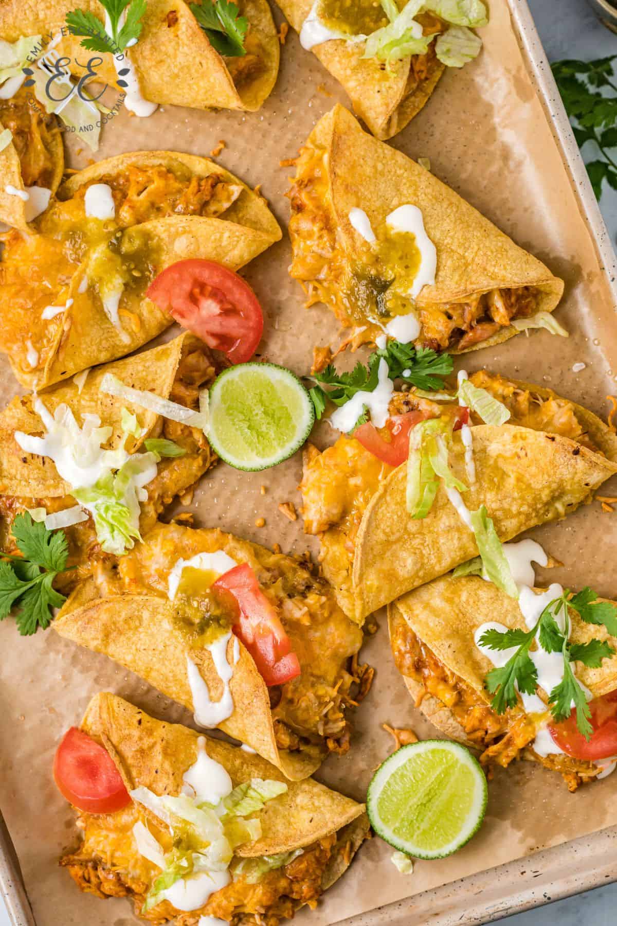 crispy chicken tacos on a baking sheet with garnish