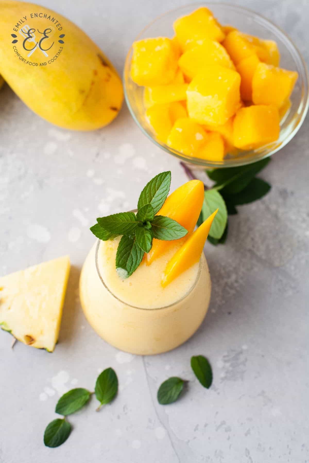 Mango Piña Colada next to bowl of sliced mango