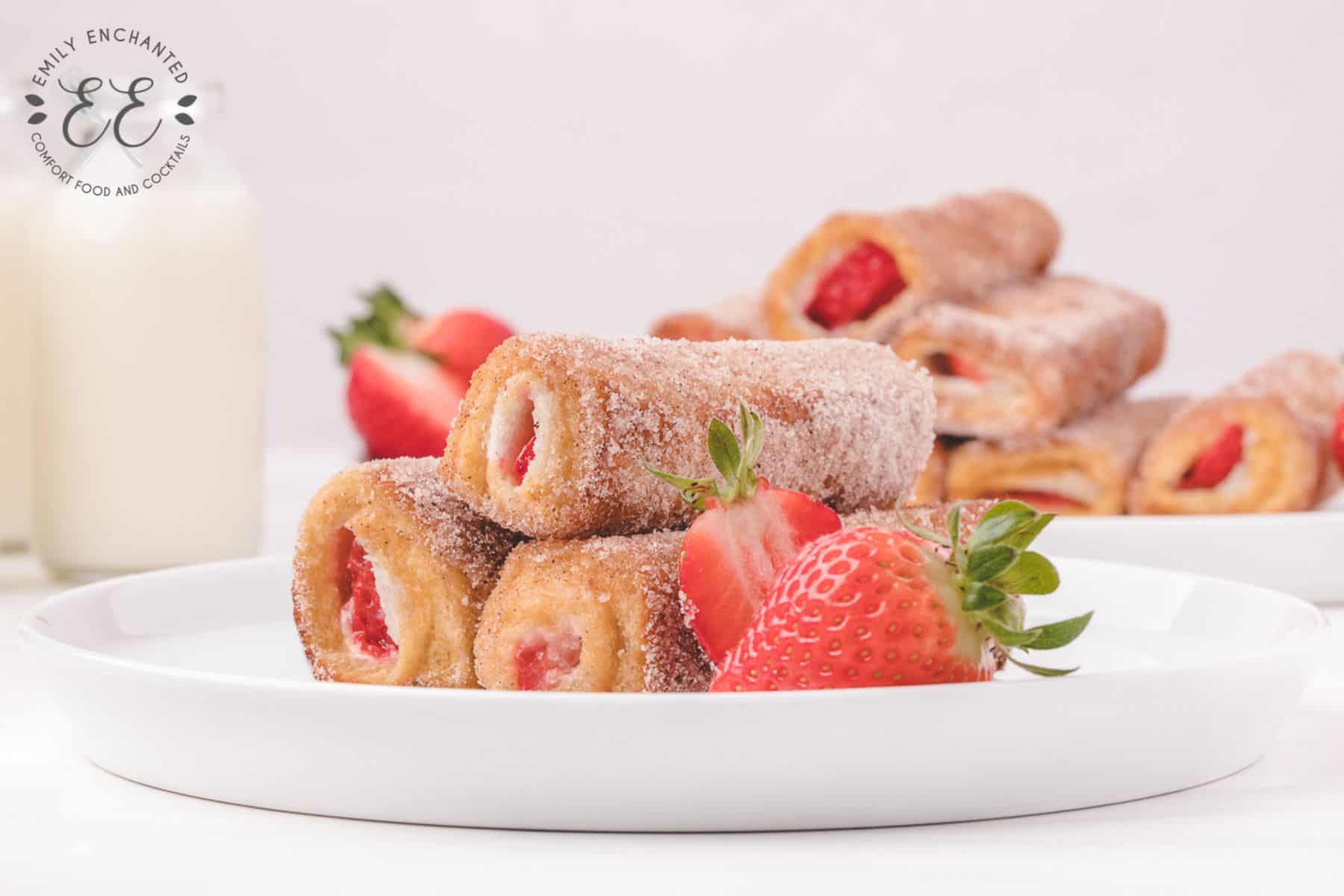 Strawberry French Toast Roll Ups stacked on a white place with fresh strawberries