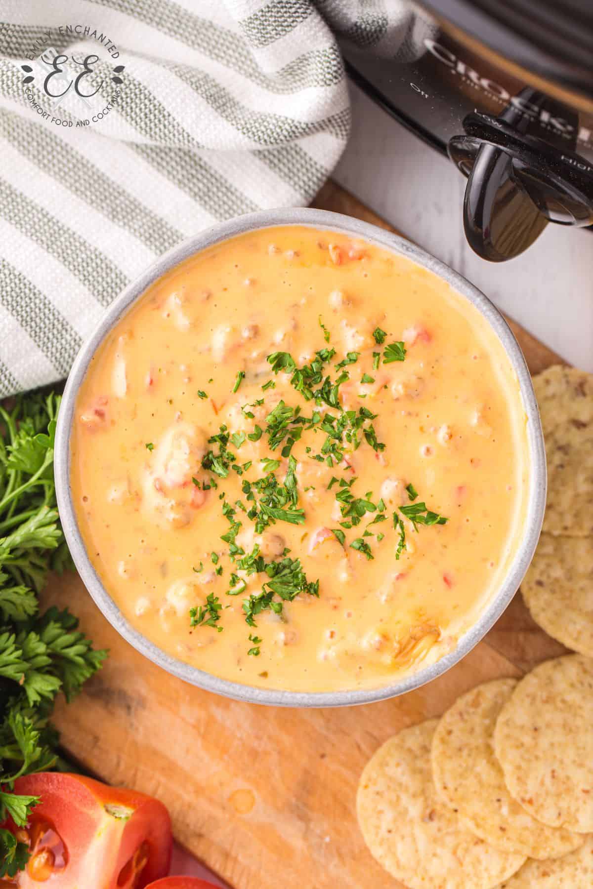 Velveeta cheese dip with sausage in a bowl with garnish