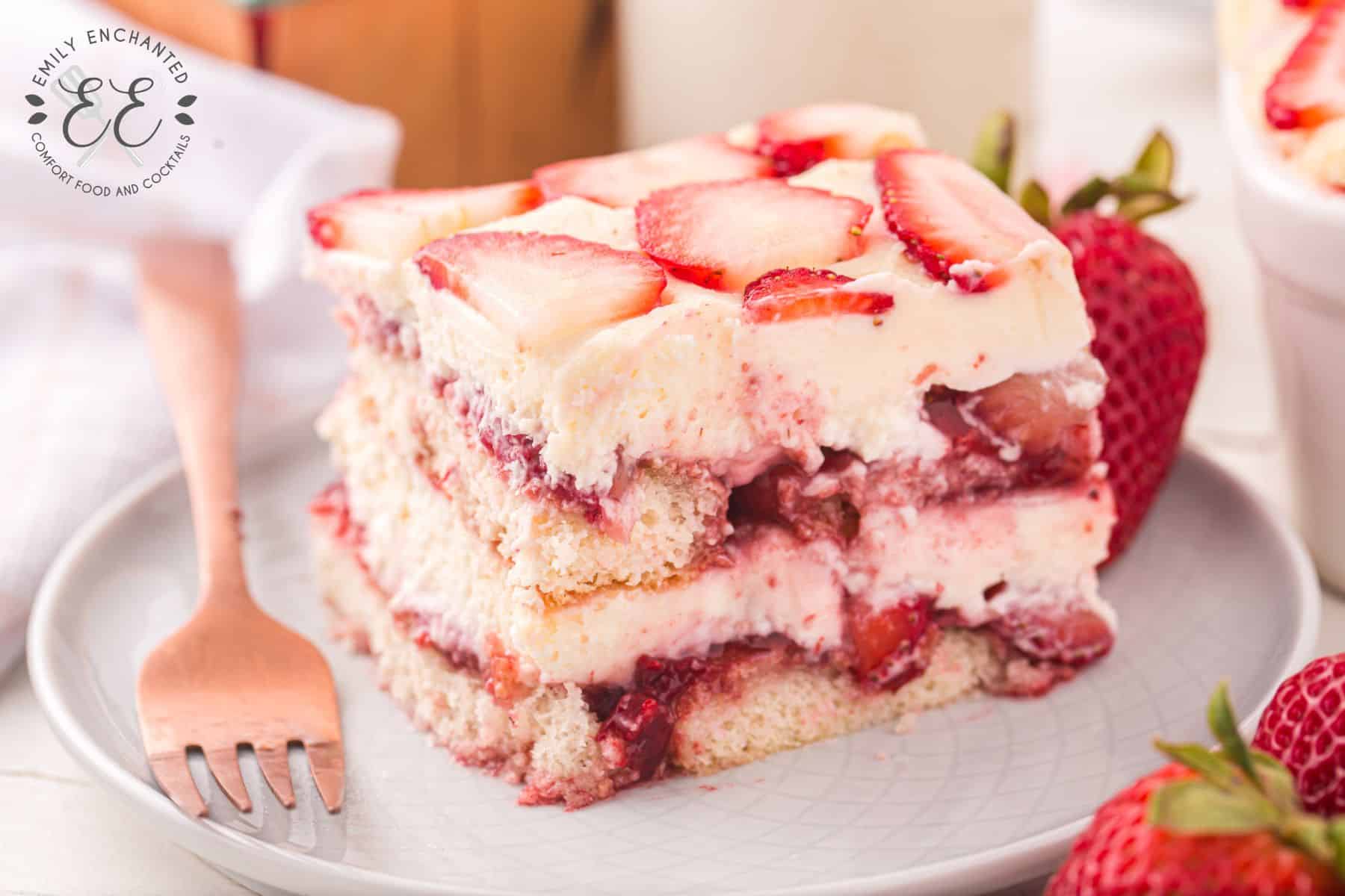 Tiramisu with Strawberries slice on a white plate with rose gold fork